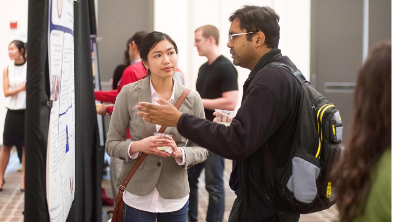 Two students talking next about a poster presentation